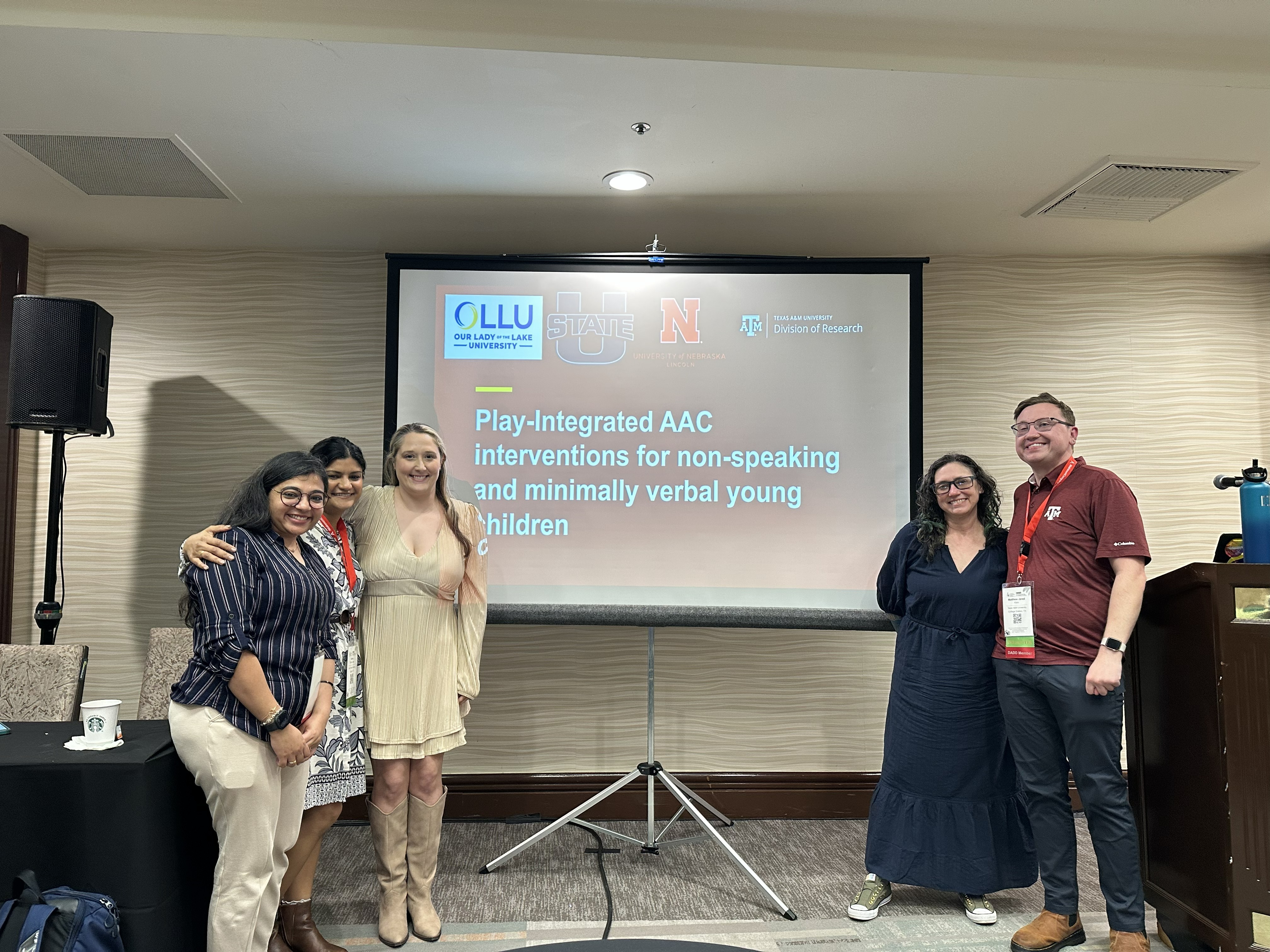 Future Dr. Anindita Banerjee, Dr. Naima Bhana Lopez, Dr. Shanna Bodenhamer, Dr. Ganz, and Future Dr. Matthew Klein (lead author) in front of their presentation slide, “Play-Integrated AAC Interventions for Non-Speaking and Minimally Verbal Young Children,” at DADD 2026.