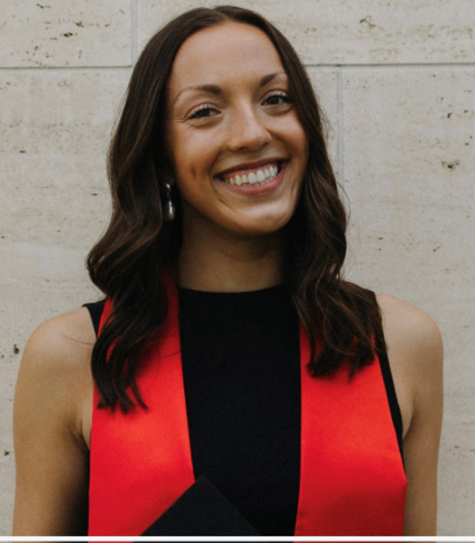 Cassidy Turner, former C2C GA, smiling with brown hair and wearing a black top and red scarf.